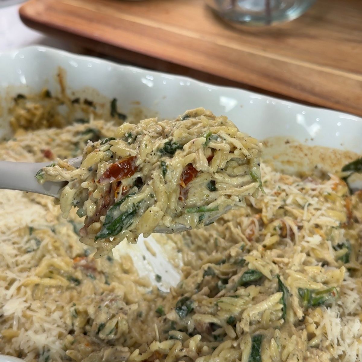 one pan orzo bake on spoon above casserole dish