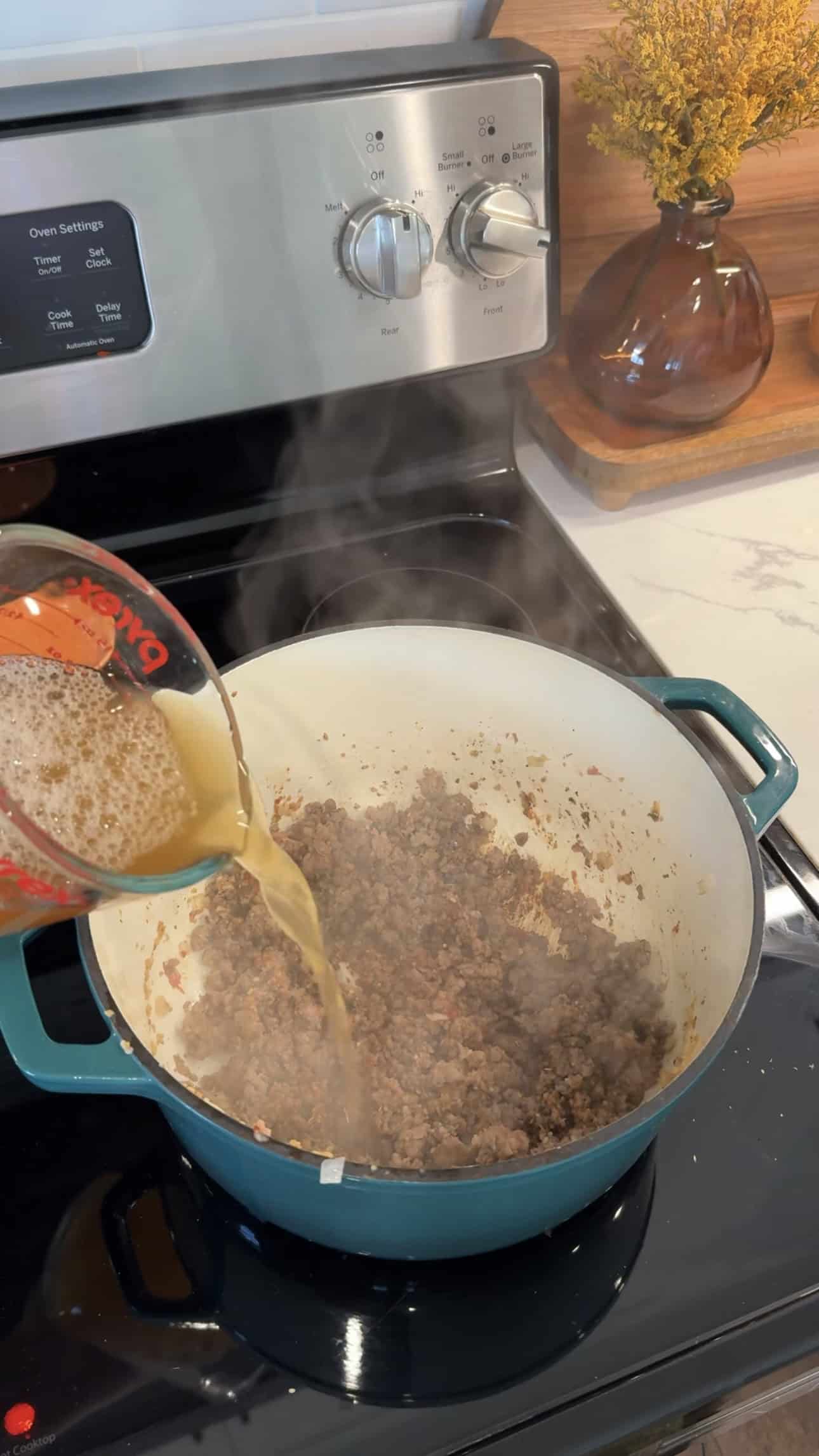 cooked italian sausage in a large pot over medium heat with cup of chicken broth pouring into pot