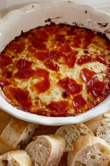 pizza dip appetizer in a baking dish with french bread slices on the side