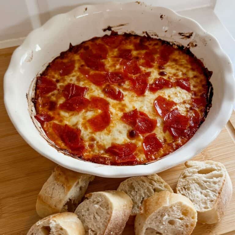 pizza dip appetizer in a baking dish with french bread slices on the side