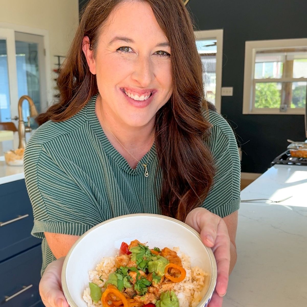 girl in green shirt holding bowl with food in it
