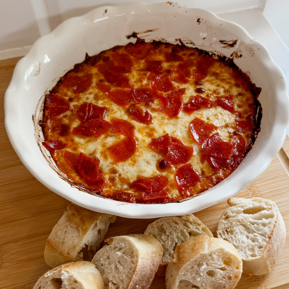 oven baked pizza party dip appetizer in pie dish with french bread slices on the side