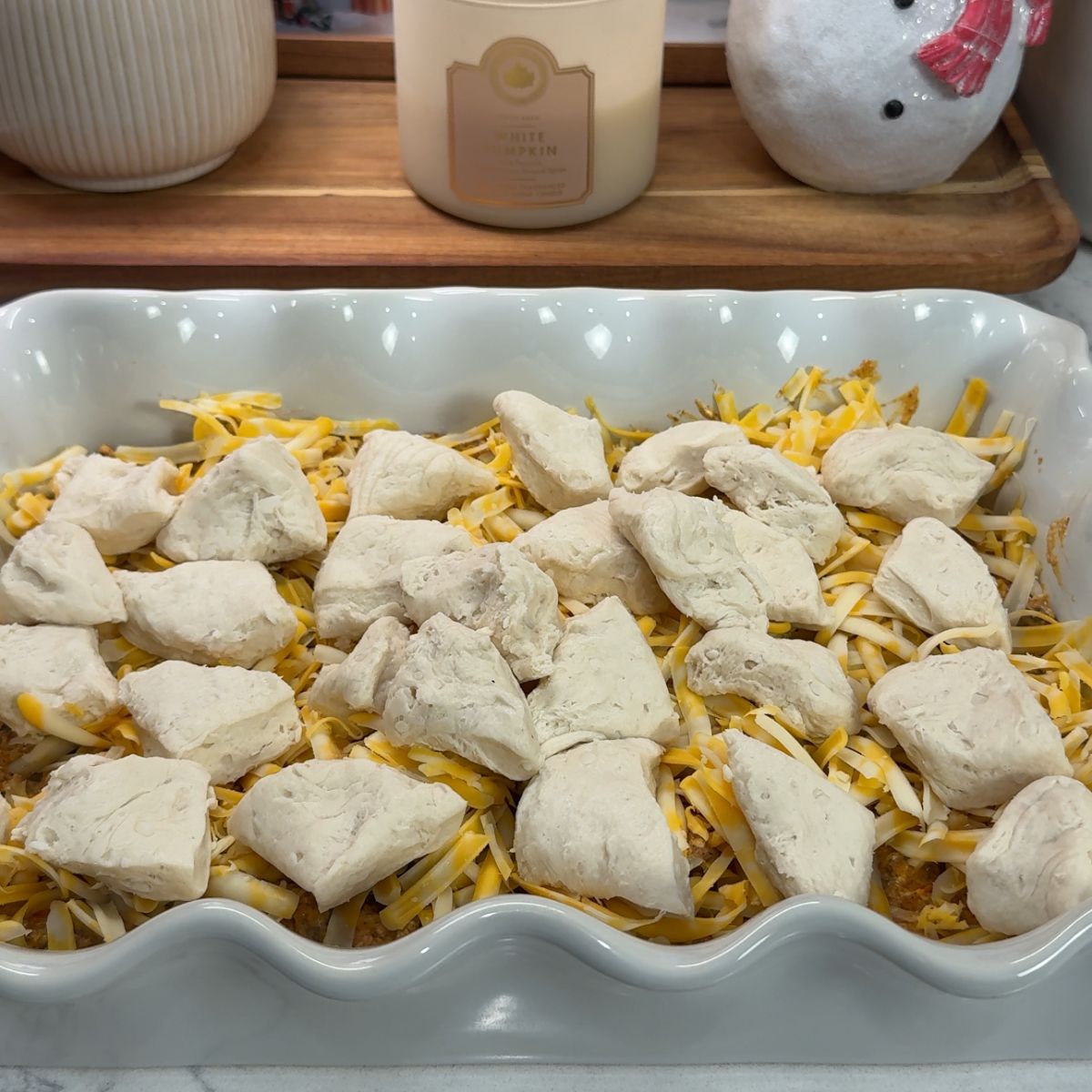 taco biscuit bake with pieces of raw biscuit dough on top of dish