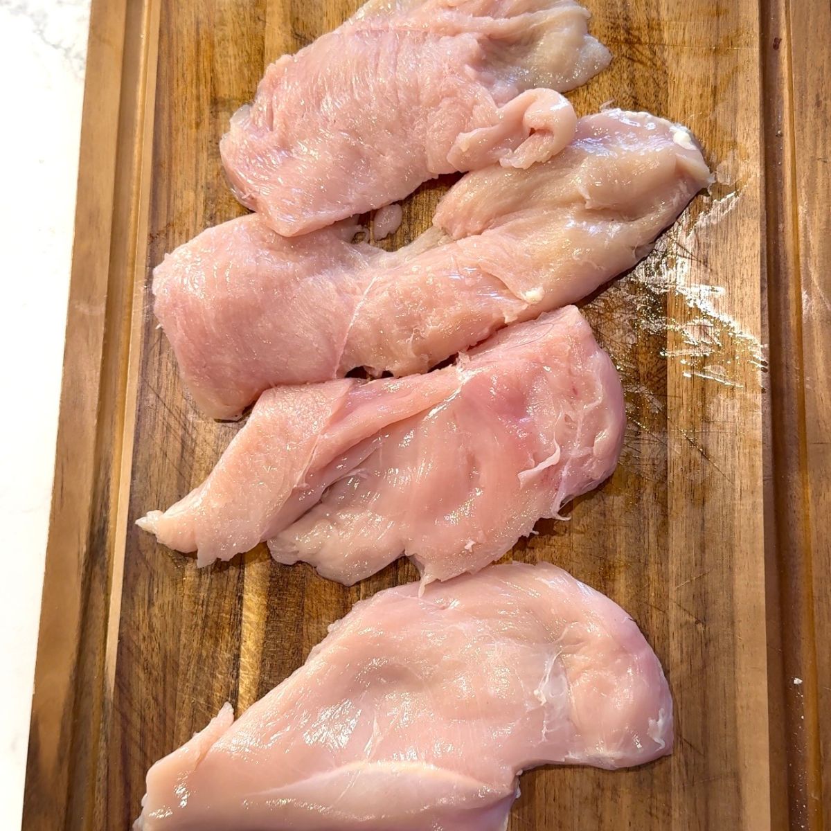 raw chicken breast on wooden cutting board