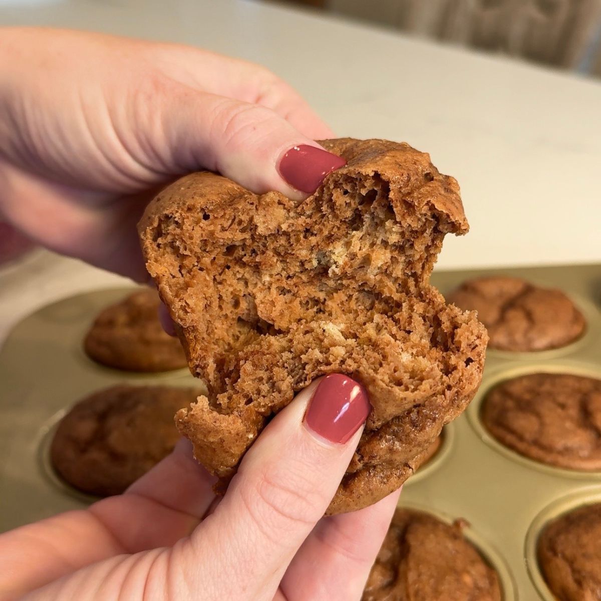 hand opening healthy protein chocolate muffins with other pastries in the background
