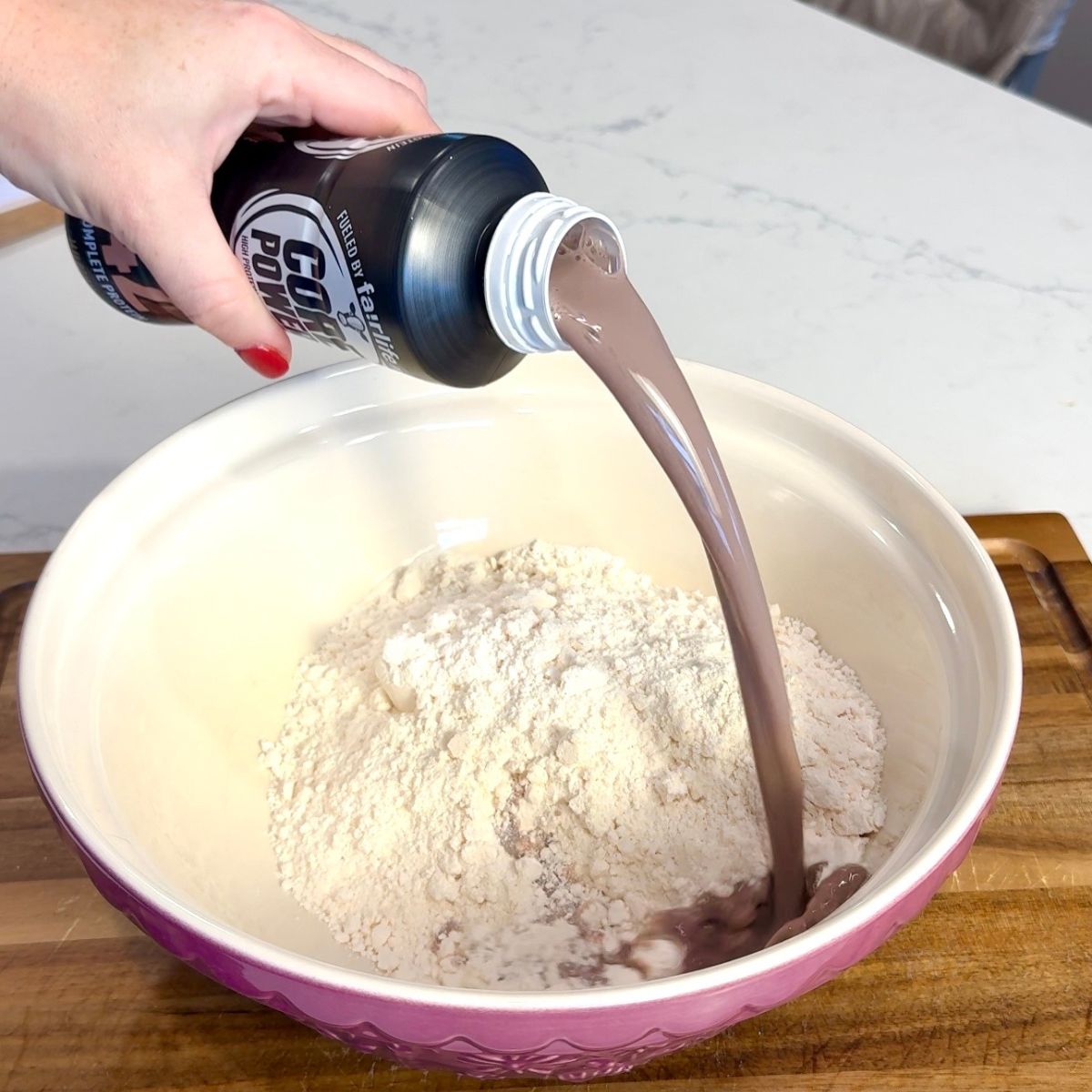 mixing bowl with ingredients. hand pouring shake into bowl
