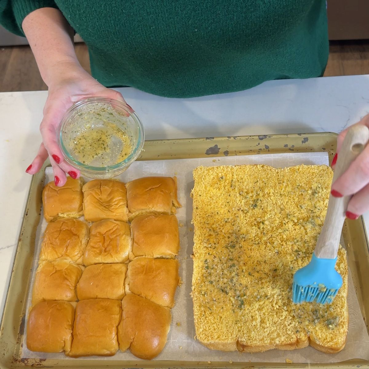 sliced slider rolls with hand brushing melted butter on bread with blue kitchen brush