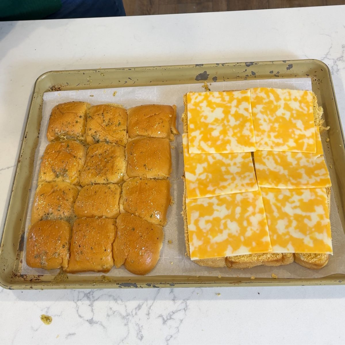 mini slider rolls sliced on 13x9 pan with cheese on bottom layer of rolls