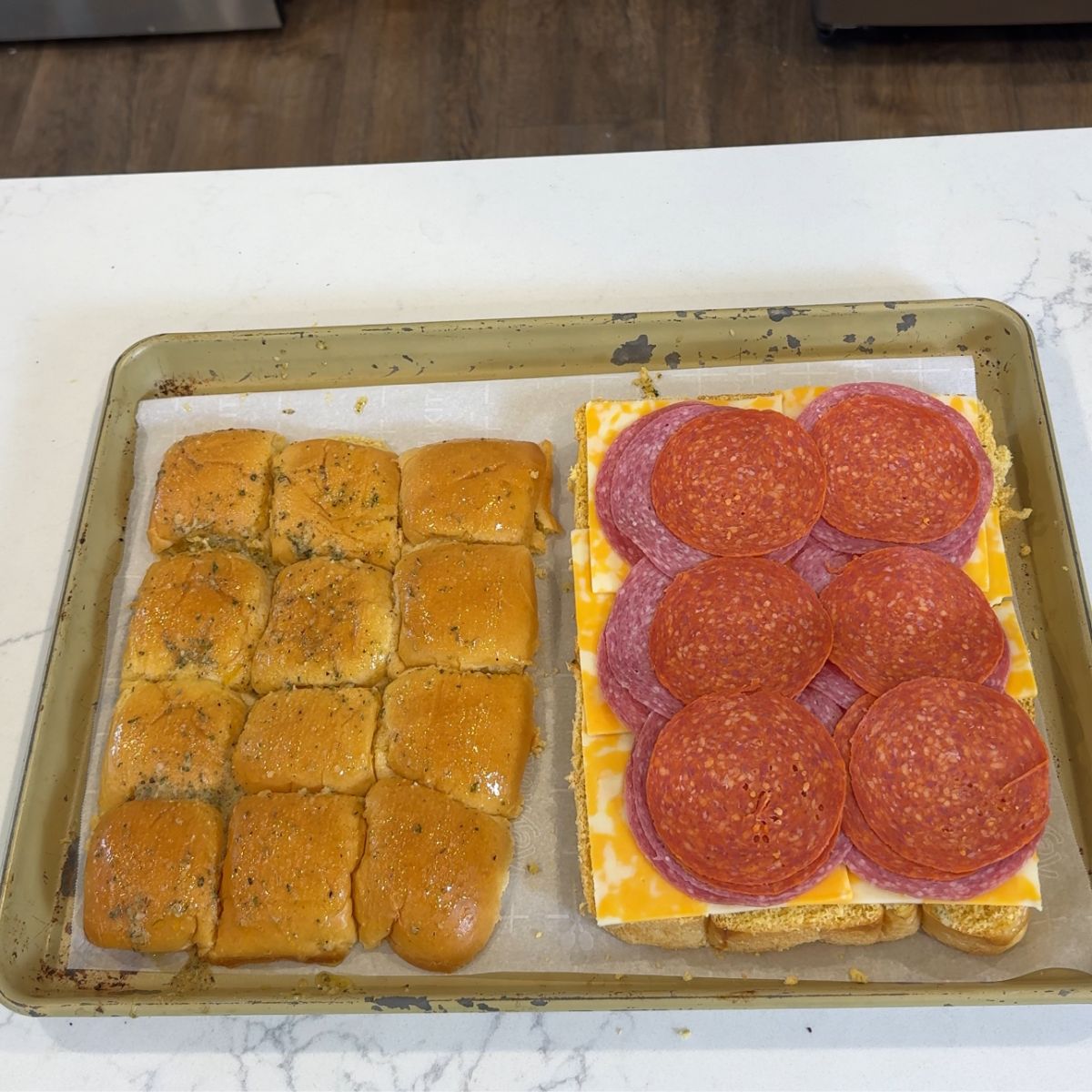 sliced mini bread rolls with layer of cheese, salami and pepperoni on tray