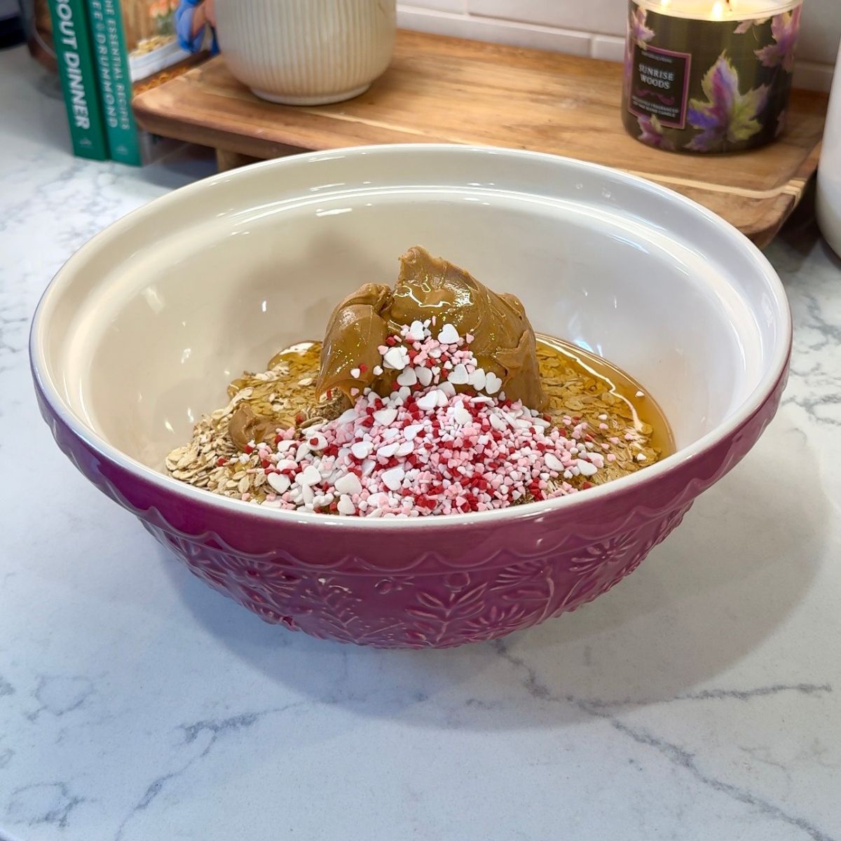 oats, honey, peanut butter, pink and red sprinkles in pink mixing bowl
