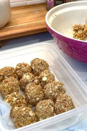 white chocolate no bake energy bites in container, with pink bowl to the side with remaining dough