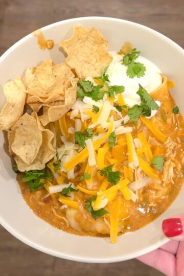 slow cooker chicken enchiladas with hand holding bowl