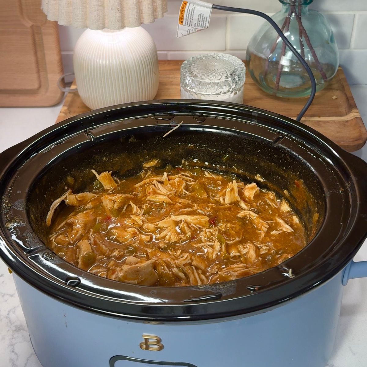 shredded chicken in warm pot with lamp in background