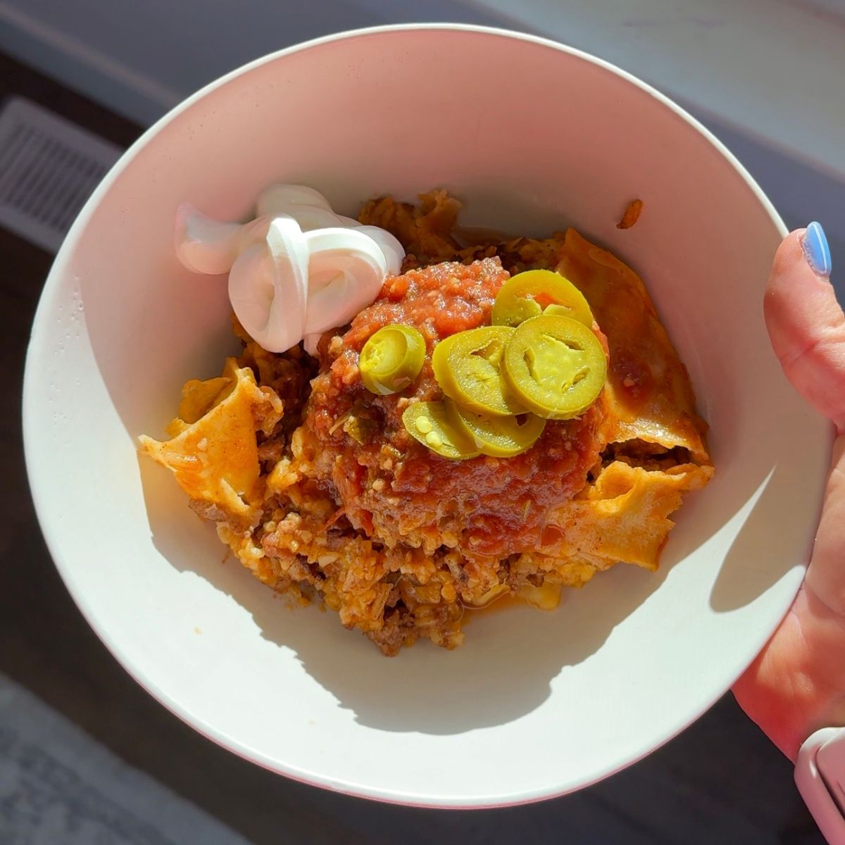 beef & rice enchilada skillet in bowl with jalapenos and sour cream