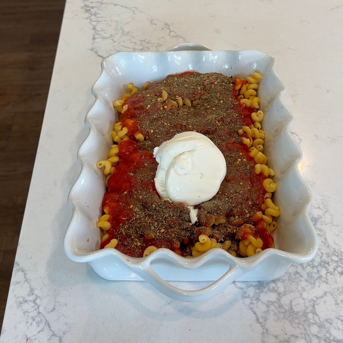 ricotta cheese, seasonings, marinara sauce and pasta shells in white dish