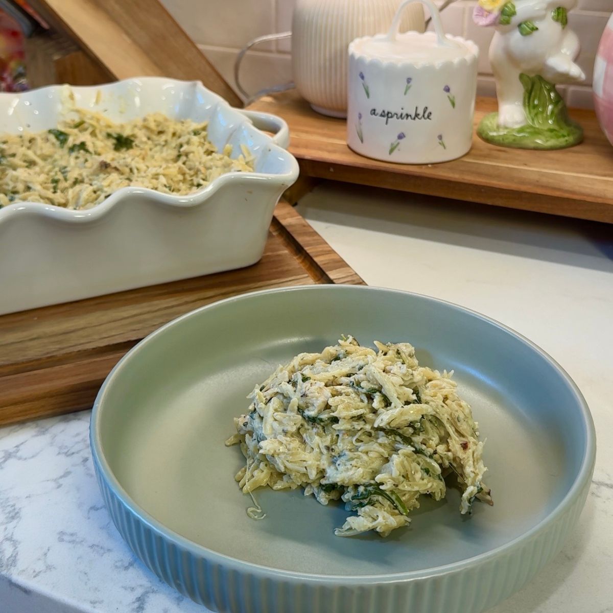 easy one pan chicken orzo on green plate with casserole dish in back on wooden board