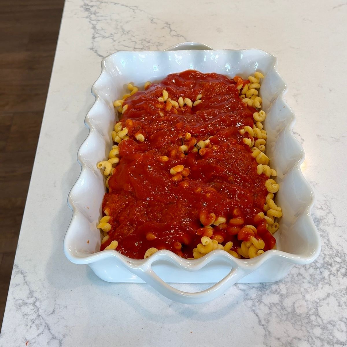 red marinara sauce on top of pasta shells in white dish