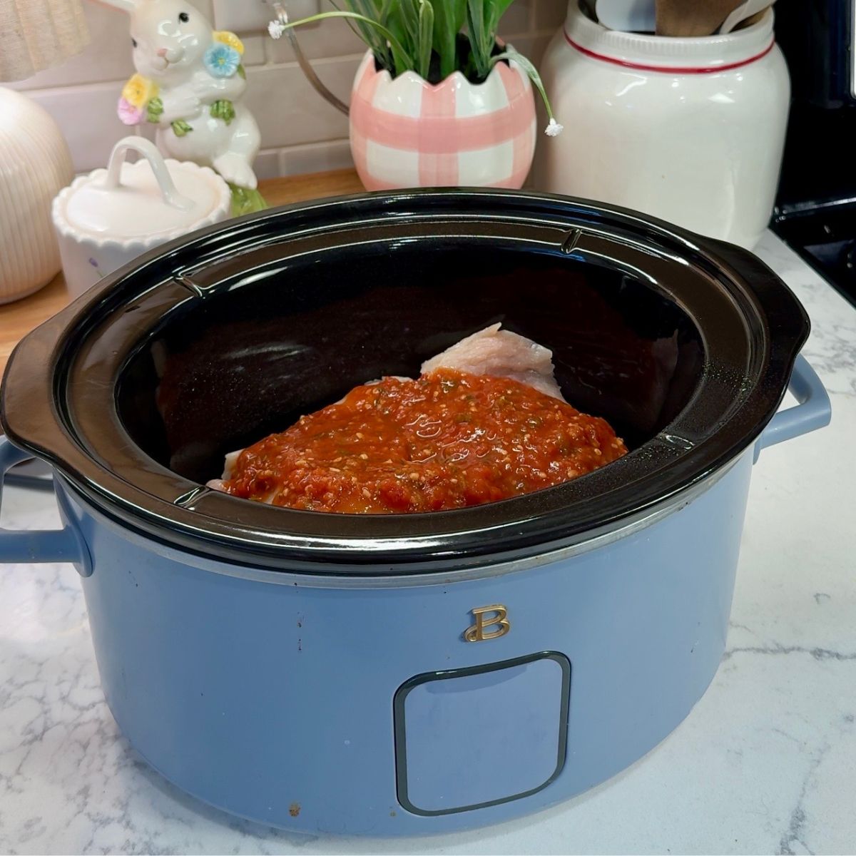 red sauce on chicken in blue slow cooker