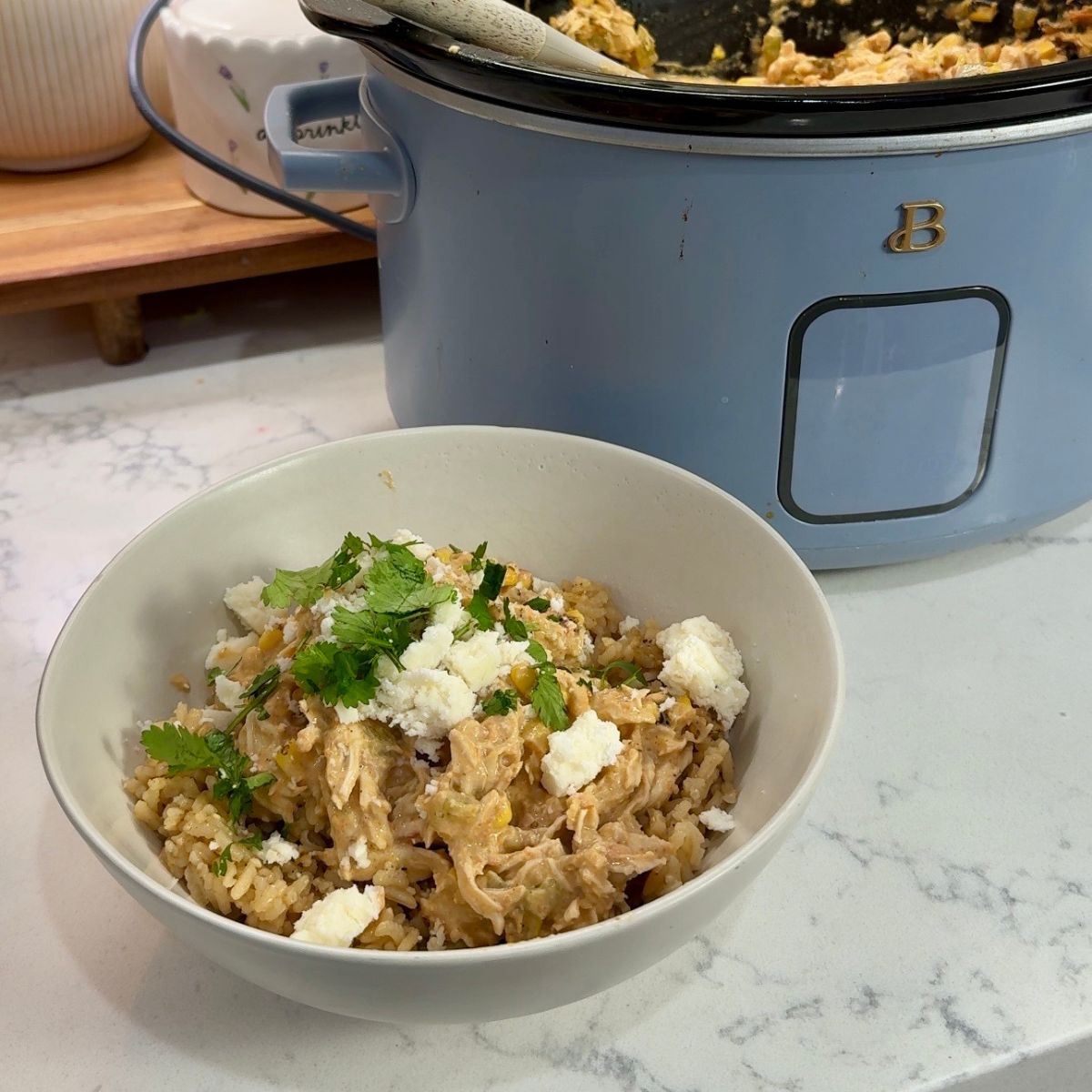 salsa chicken in bowl next to blue crockpot