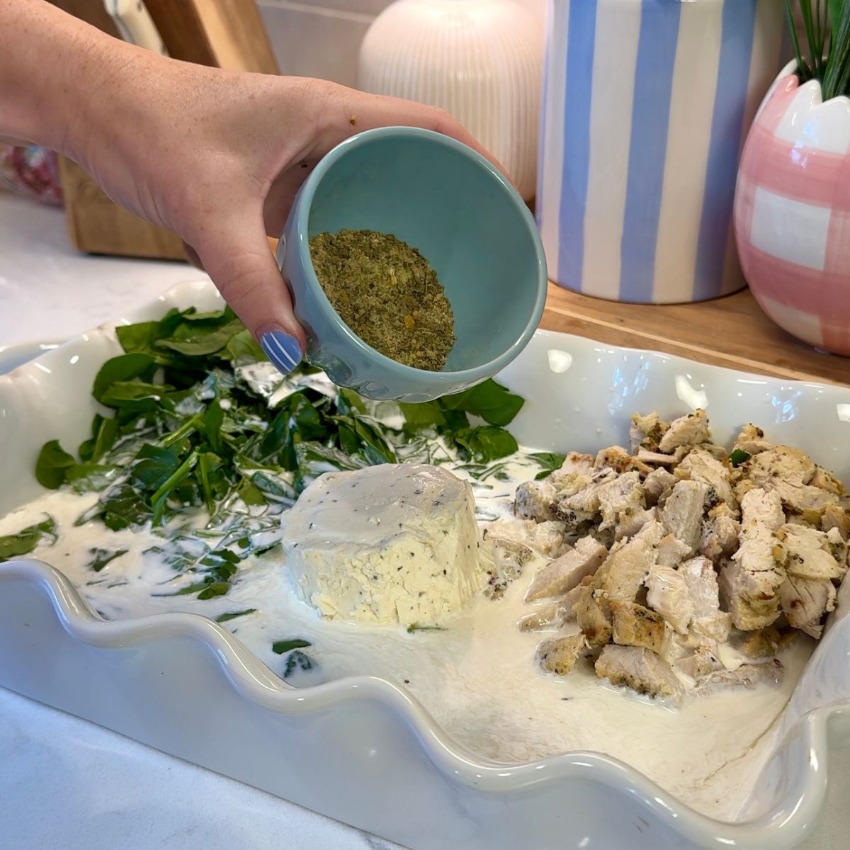 seasoning in blue container pouring into white casserole dish