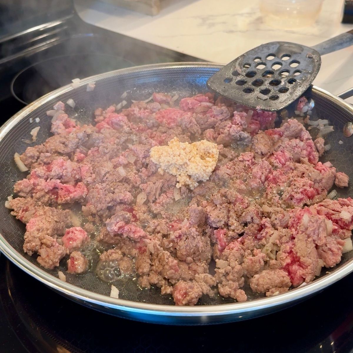 cooked beef, minced garlic and onions in pan