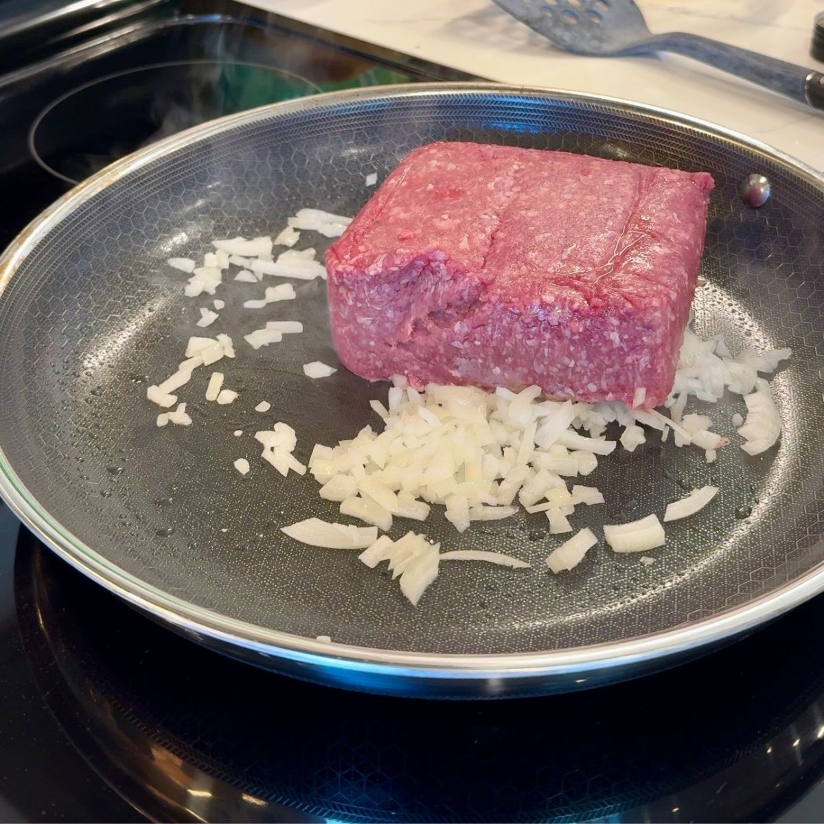 ground beef and diced onion on skillet
