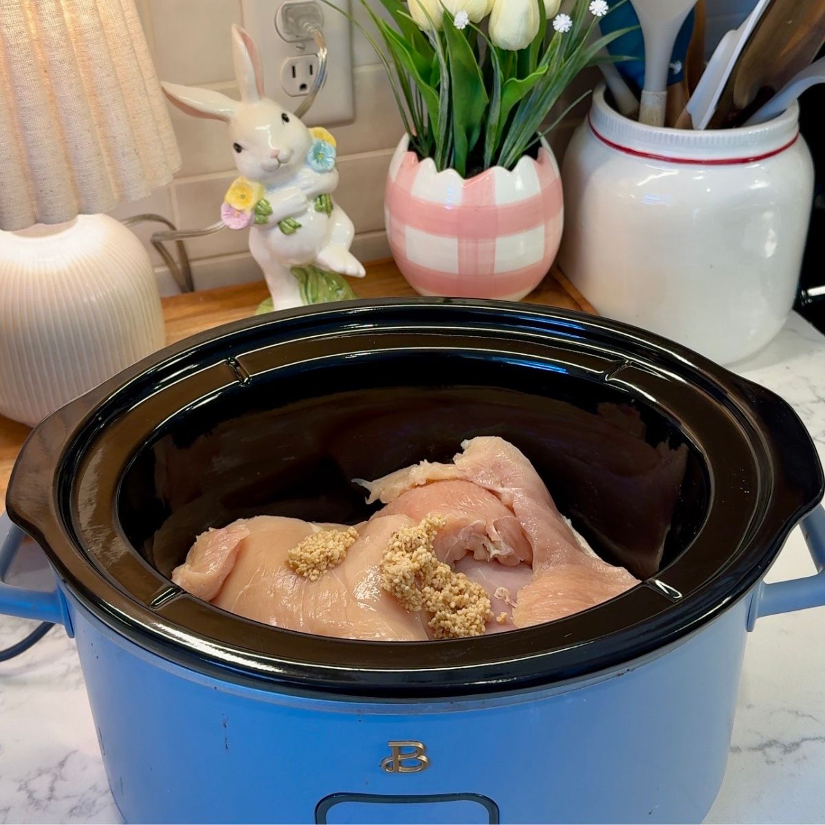 raw chicken with minced garlic in blue crock pot