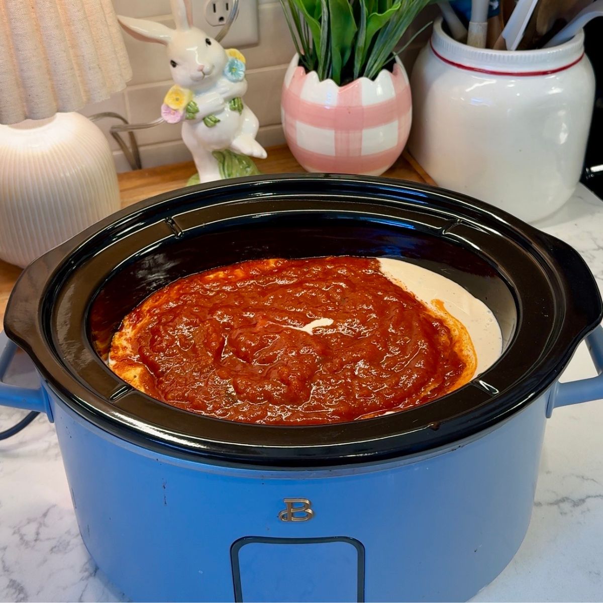 marinara and alfredo sauce on top of chicken in crockpot