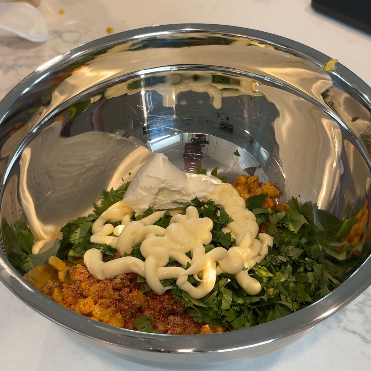 mayo, sour cream, cilantro, and seasonings added to corn in bowl