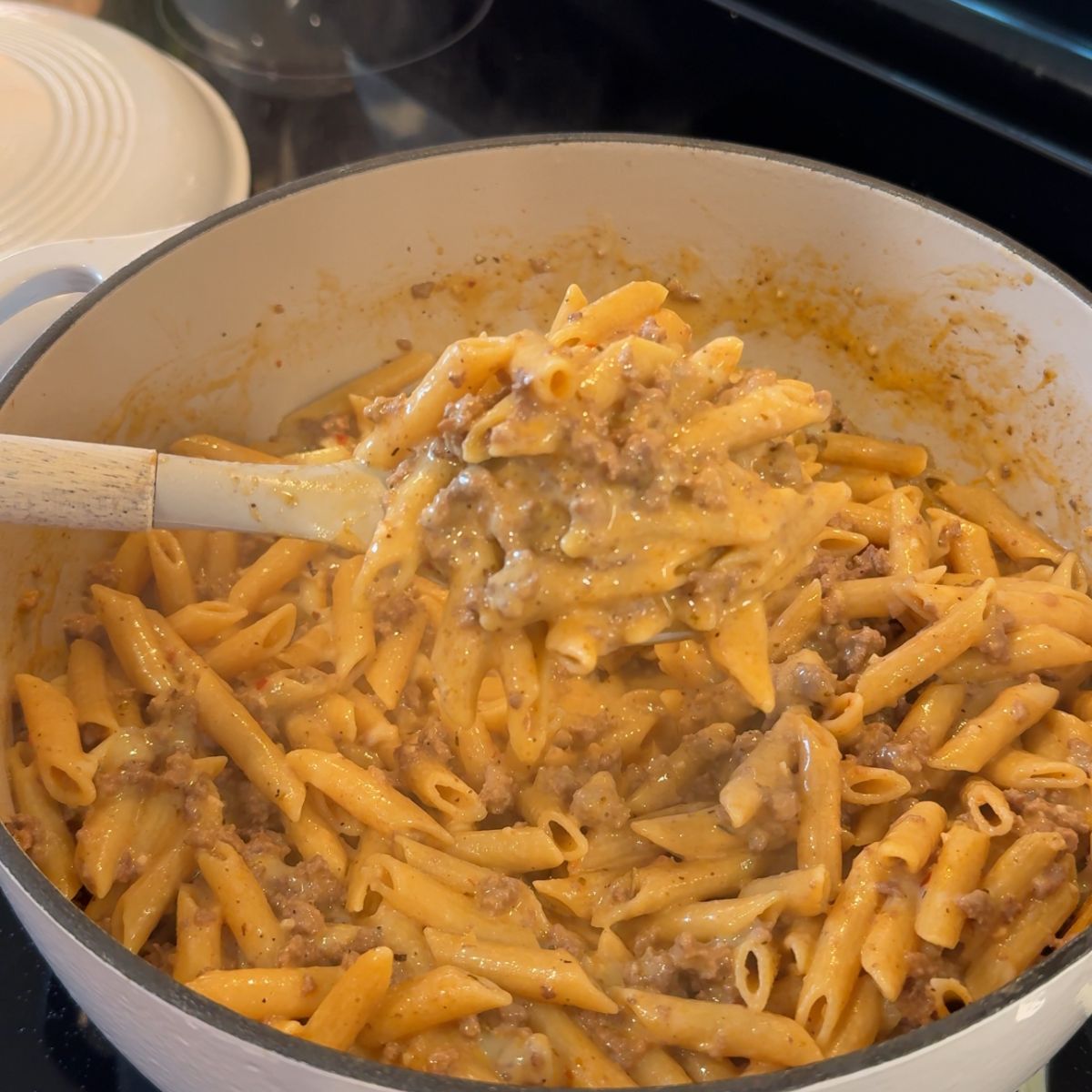 spoon holding pasta over dutch oven