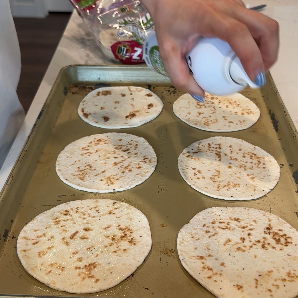 olive oil sprayed on tortillas on baking tray