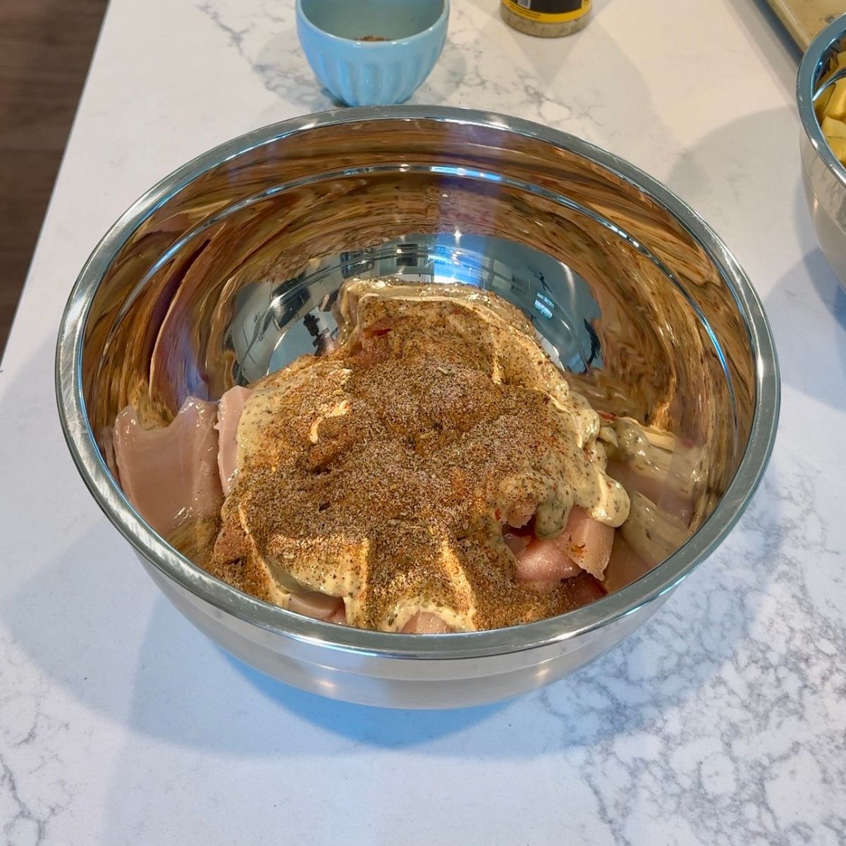 chicken in bowl with seasonings and sauce