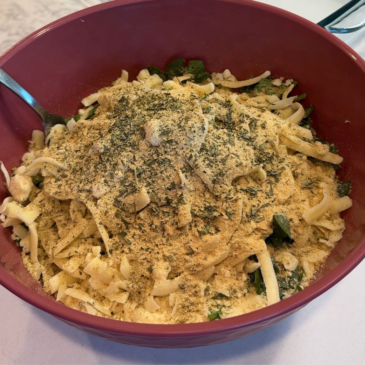 seasonings on top of chicken mixture in pink bowl