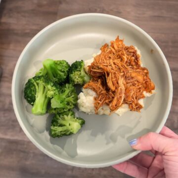 slow cooker honey chipotle chicken over potatoes with broccoli on green plate