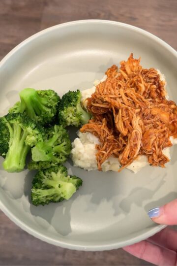 slow cooker honey chipotle chicken over potatoes with broccoli on green plate
