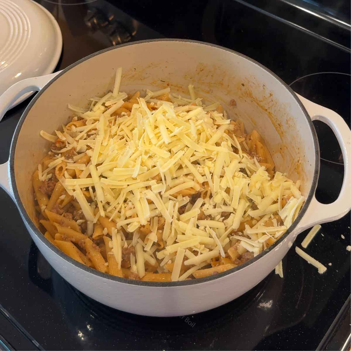 shredded cheese on top of cooked beef and pasta