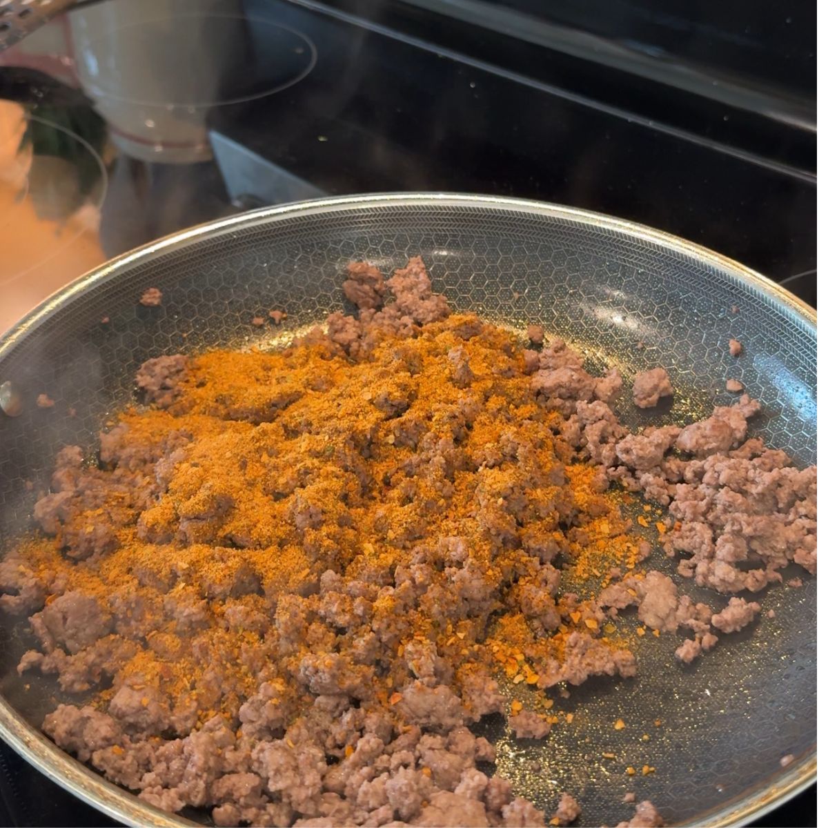 taco seasoning added to cooked ground beef in pan