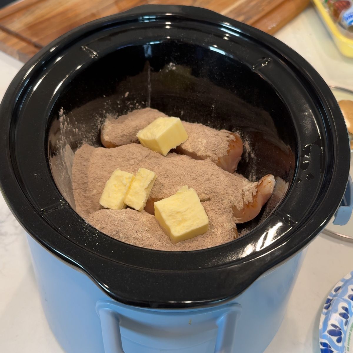 chicken in crockpot with seasonings and butter