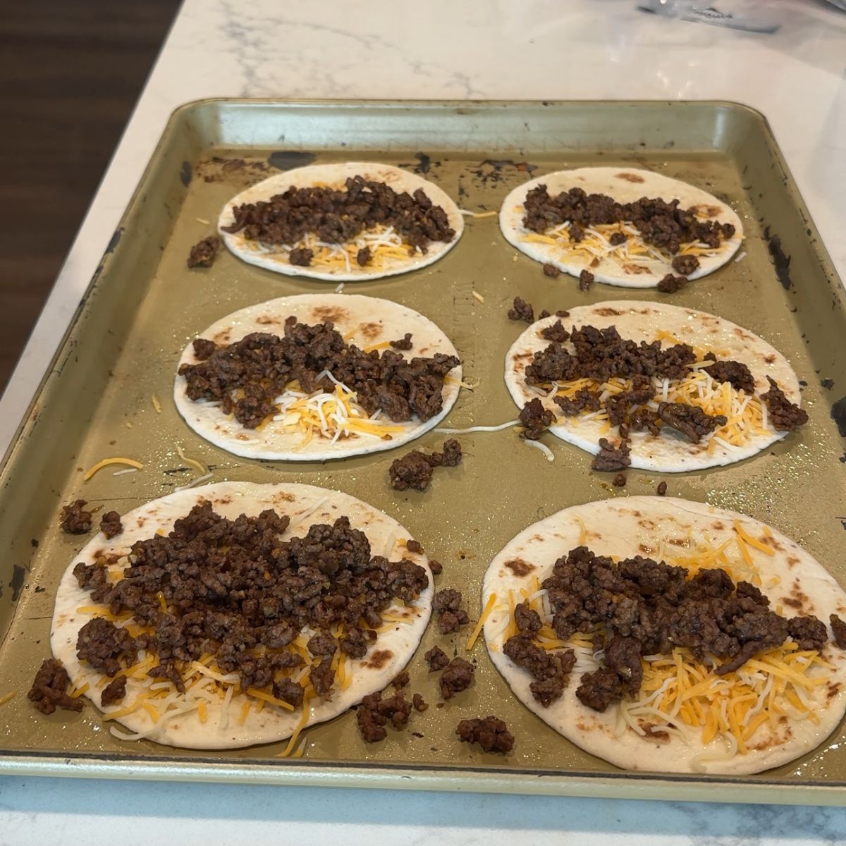 ground beef on cheese and tortillas on baking tray
