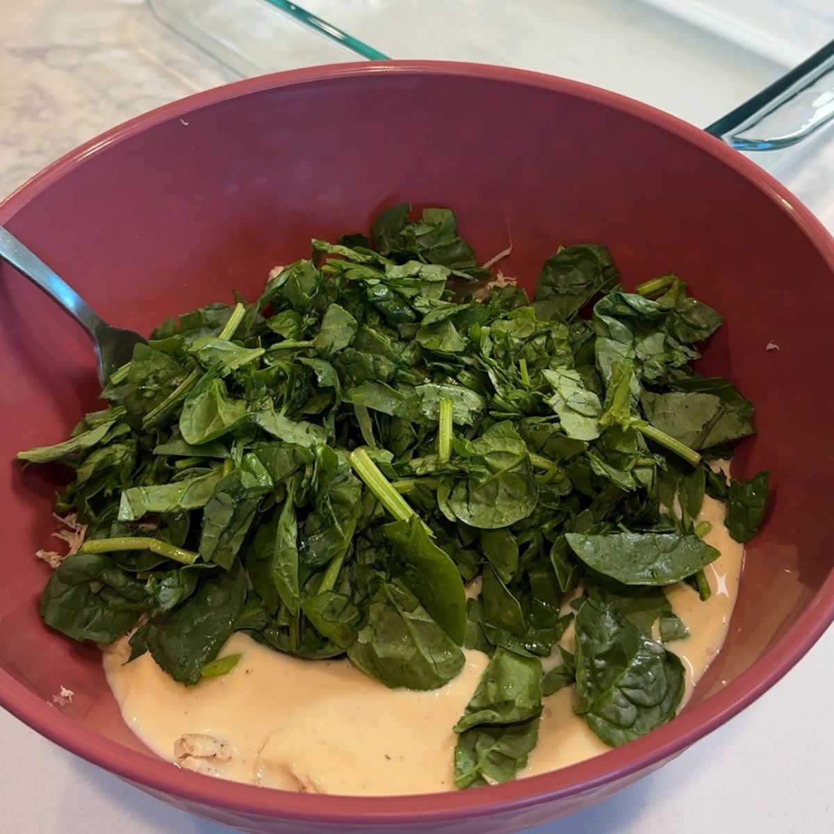 spinach on chicken mixture in pink bowl