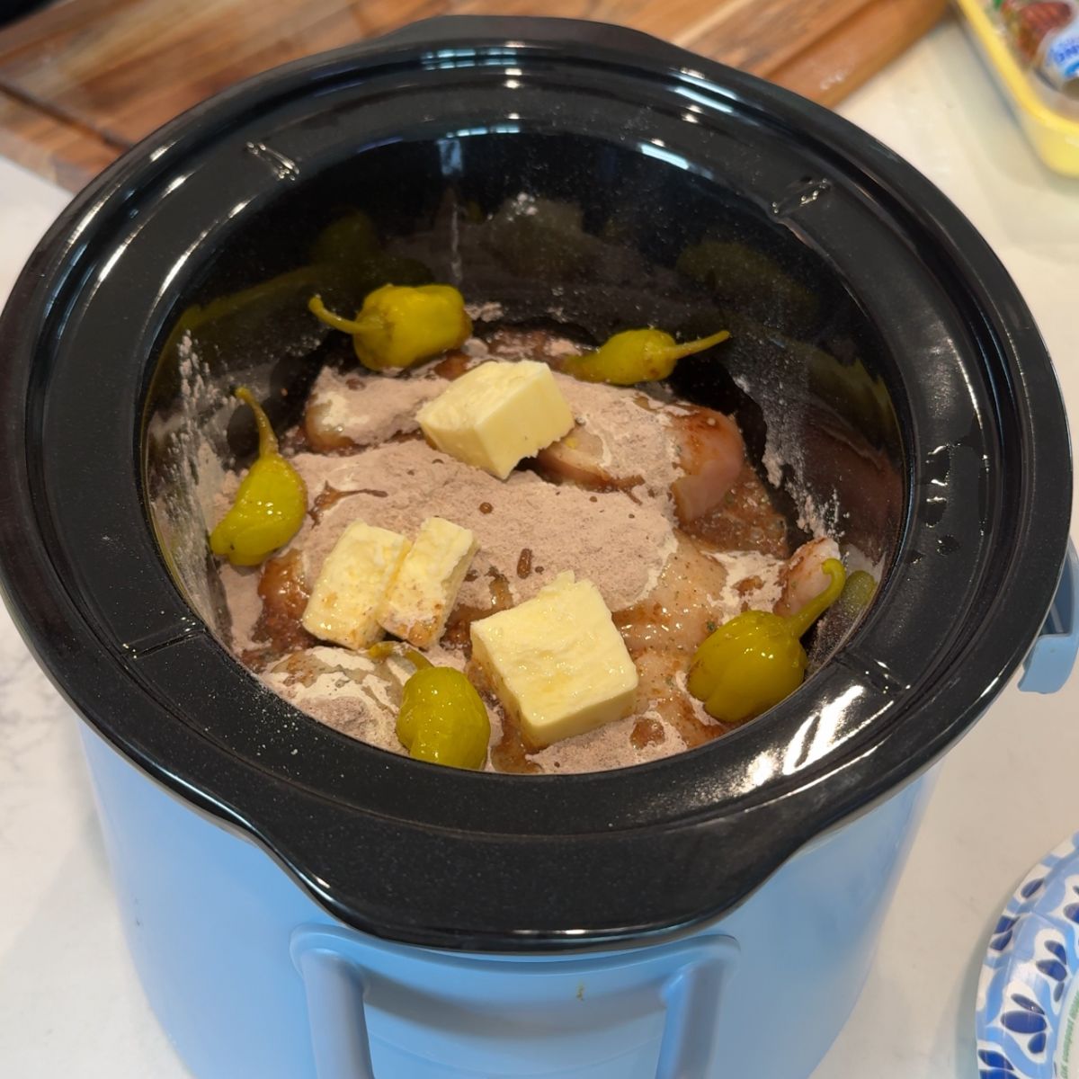pepperonicini peppers added to chicken, seasonings and butter in slow cooker