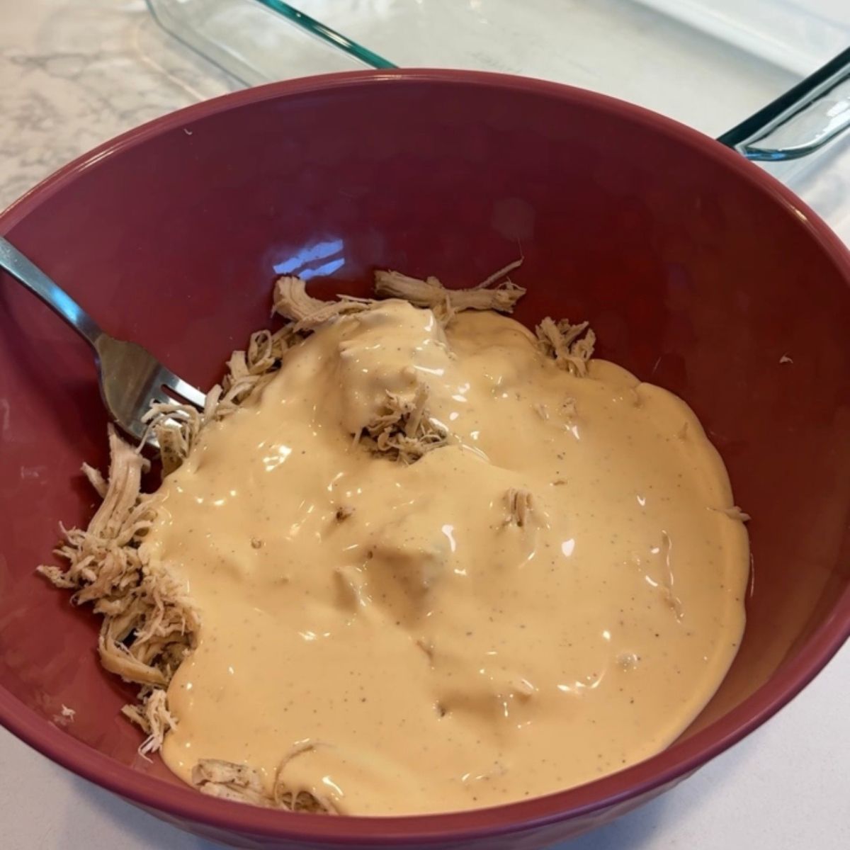 chicken and alfredo sauce in pink mixing bowl