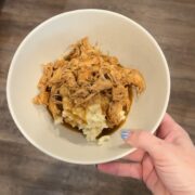 chicken over potatoes in bowl with hand