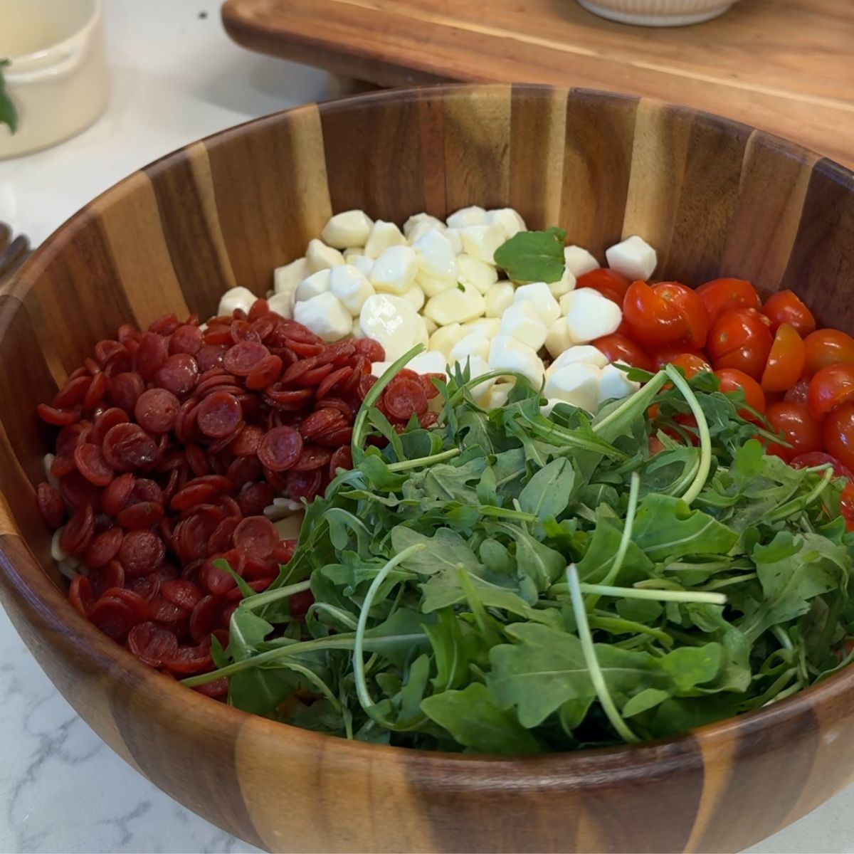 mozzarella, pepperoni, tomatoes, arugula and basil in bowl