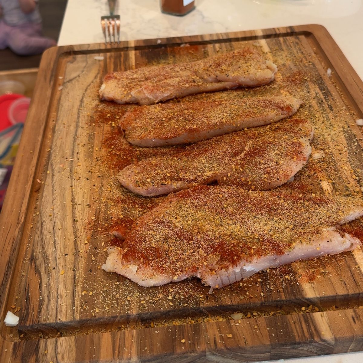 four raw chicken breast with seasoning on wooden cutting board 