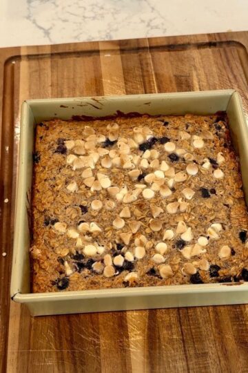 blueberry baked oatmeal in pan with wooden board underneath