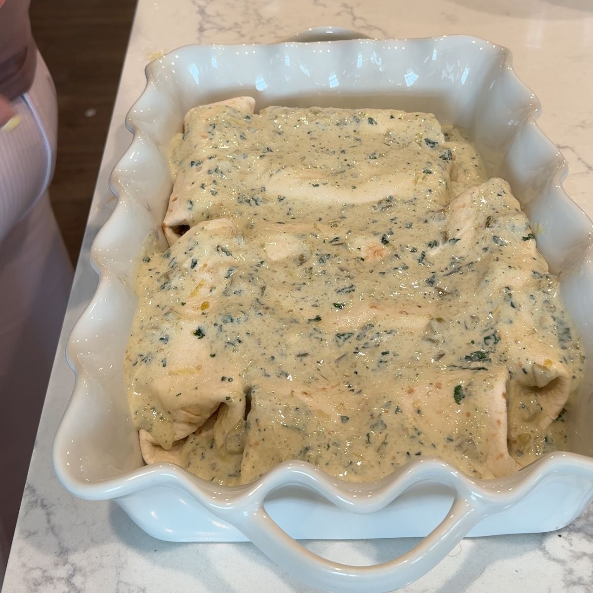 enchilada sauce on top of tortillas in baking dish