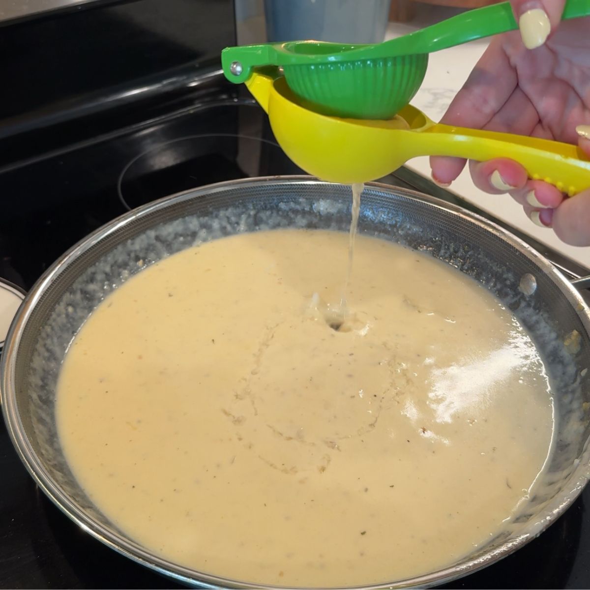 lemon being squeezed over smothered cowboy butter cream sauce in skillet