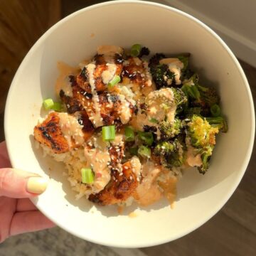bang bang chicken with broccoli and rice in bowl and hand holding bowl