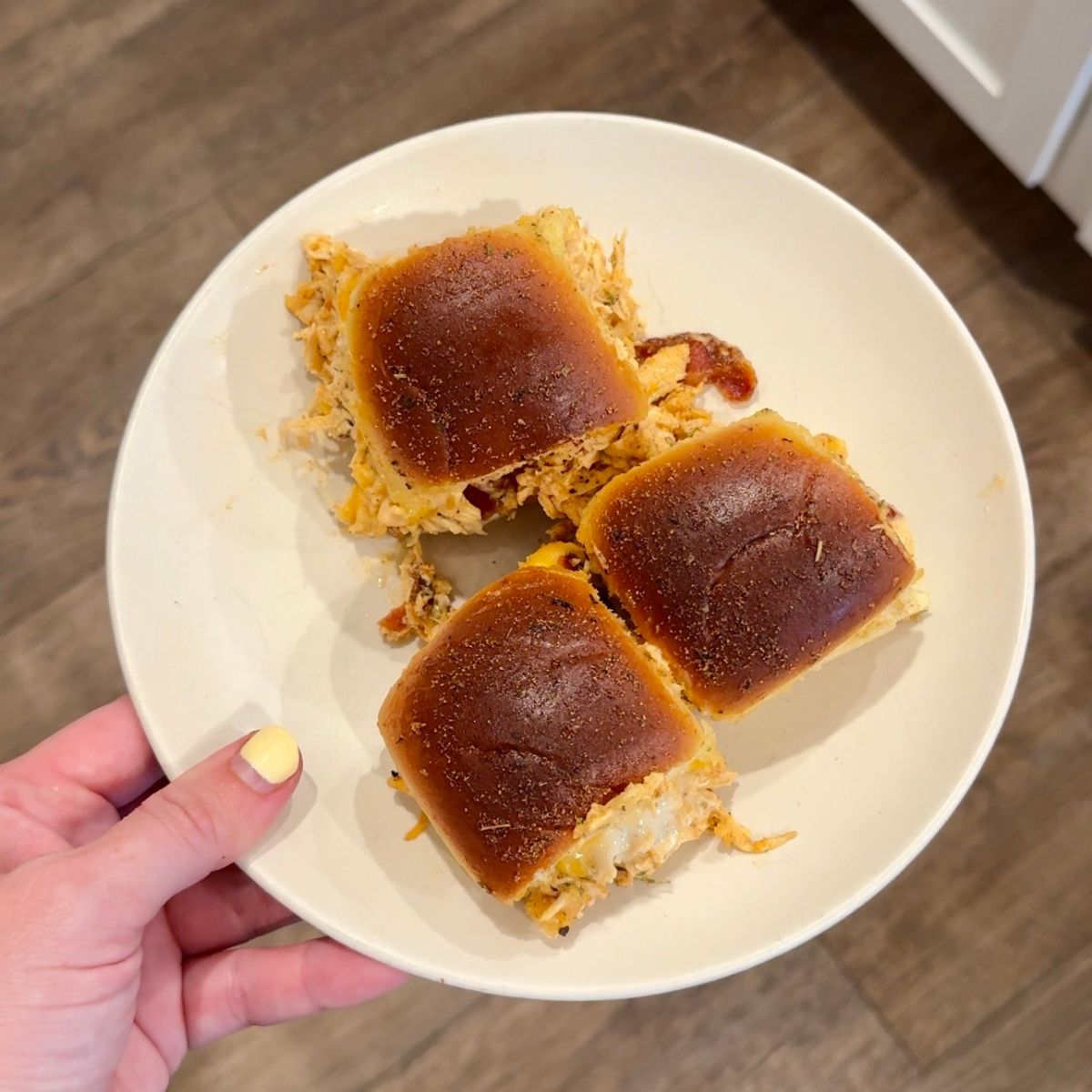 3 chicken bacon ranch sliders with hand holding white plate